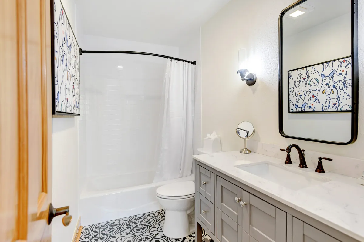 A stylish, inviting bathroom with a modern vanity and sink, decorative artwork on the wall, and a glass-enclosed shower area. The space is well-lit and feels fresh and serene, ideal for relaxation and self-care.