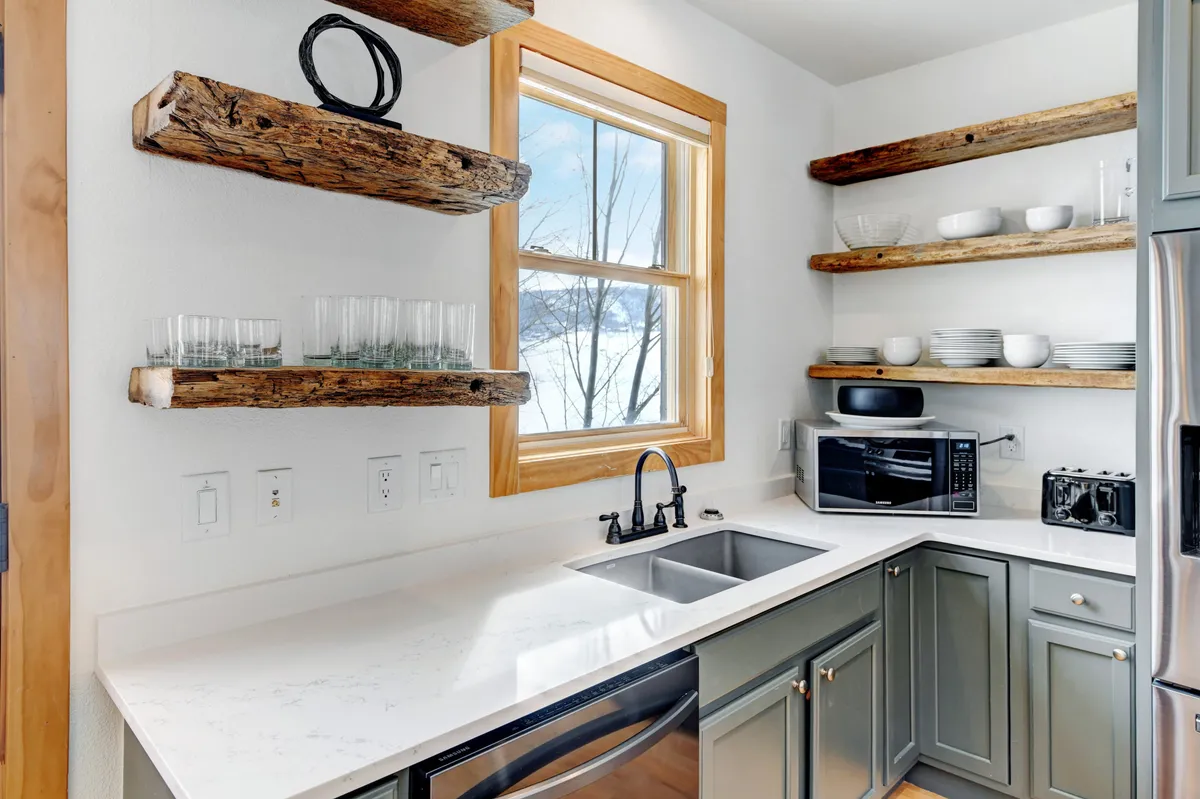 A kitchen scene with a modern sink, rustic wood shelves, and a window offering a scenic view. The space feels bright and welcoming, ideal for preparing a meal while enjoying the Colorado landscape.