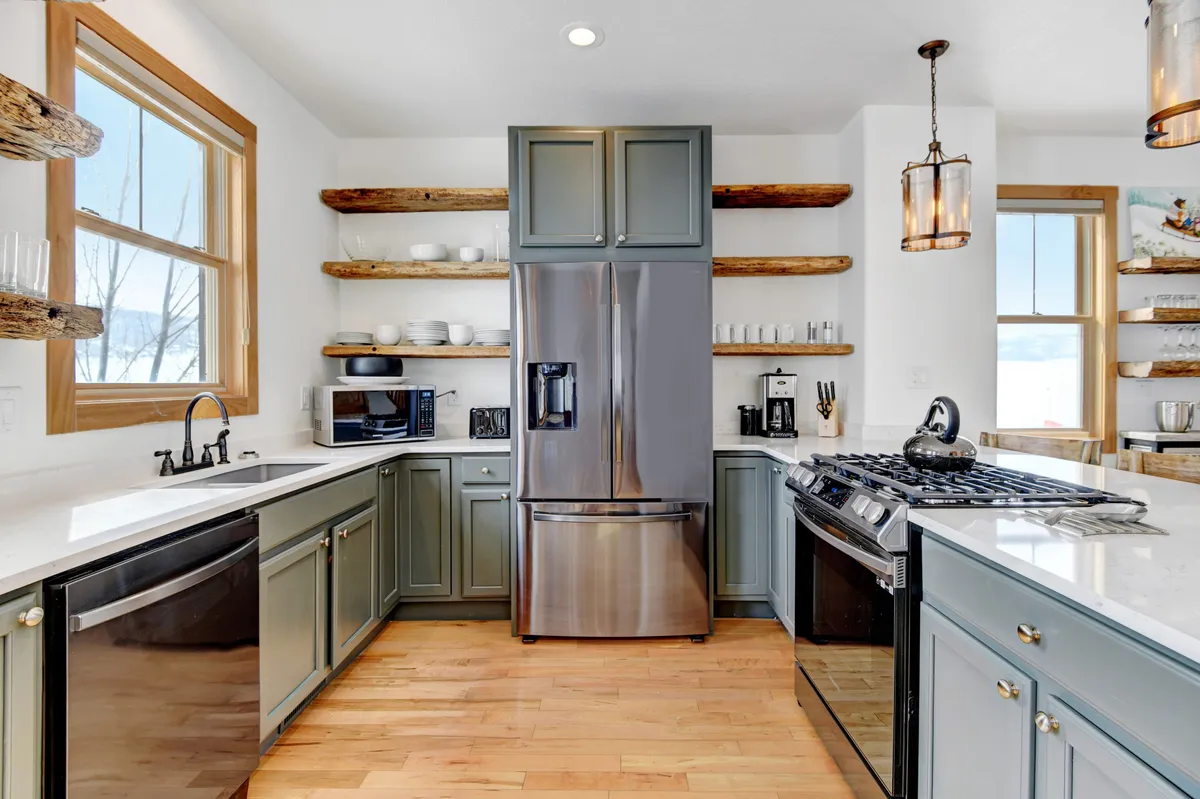 A modern kitchen with stainless steel appliances, a gas stove, open shelves with dishware, and warm wooden accents. The setting is perfect for family gatherings, meal prep, and entertaining guests, with a relaxed and welcoming vibe.