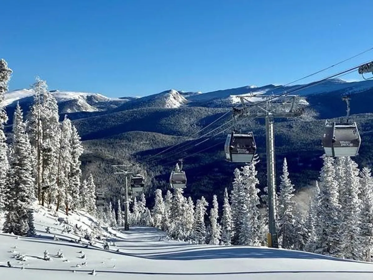 A picturesque winter scene featuring a ski lift, snow-covered trees, and a stunning mountain range. The landscape evokes the excitement and accessibility of nearby Granby Ranch for skiing, snowboarding, or simply enjoying the outdoors.
